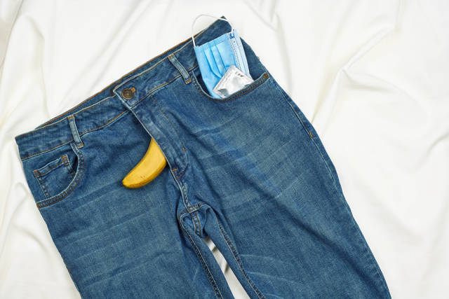 Face mask and condom in the pocket of jeans with banana
