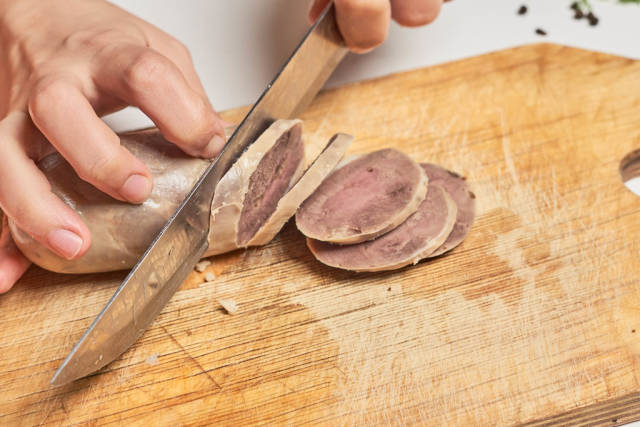 Female cutting a horse meat based delicatessen sausage on the cutting board