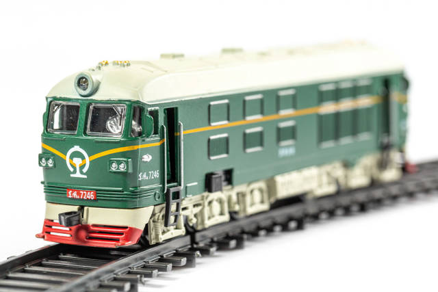 Metallic model of a green train on with rails, close-up
