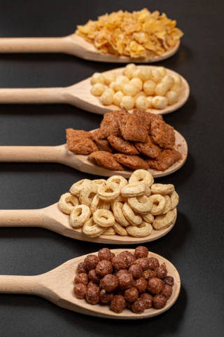 Close-up, wooden spoons with breakfast cereals on a dark background