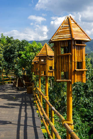Holzbrücke in einer Kaffeeplantage mit Bambus Geländer und Vogelhäusern im Me Linh Coffee Garden in Dalat, Vietnam