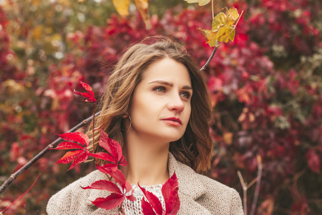 Portrait of a girl on an autumn background with red leaves