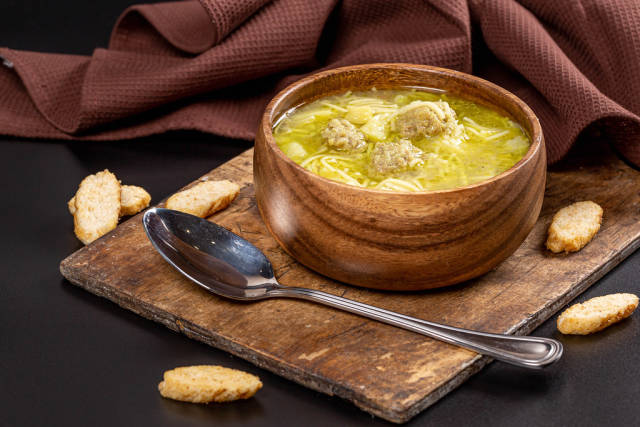Bowl of soup with meatballs on old wooden kitchen board