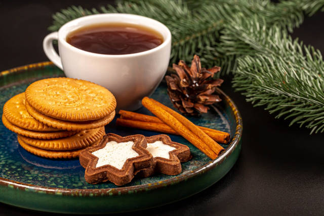 Christmas background with cookies, a cup of coffee, cinnamon sticks and branches of a christmas tree