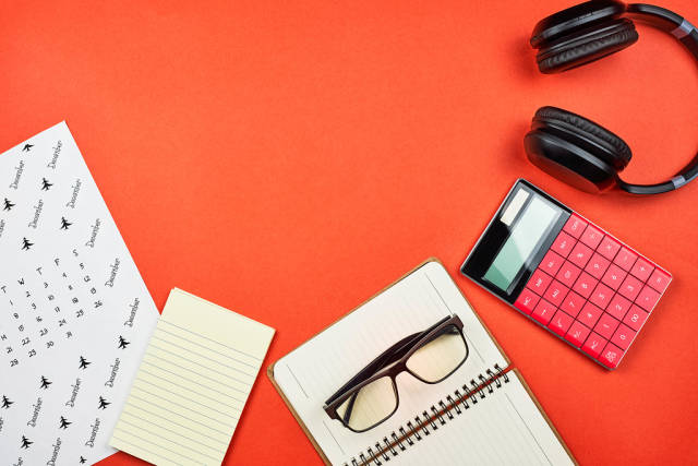 Flat lay arrangement of office supplies on a bright red background