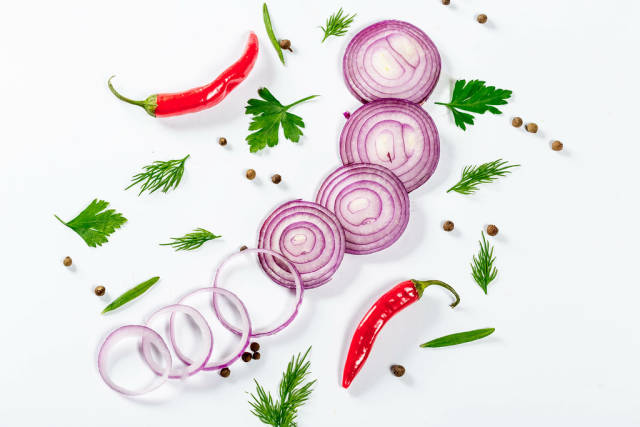 Sliced rings of purple onion with spices and chili