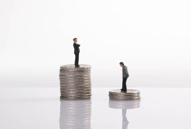 Close up of businessman miniature people figures standing on stack of coins