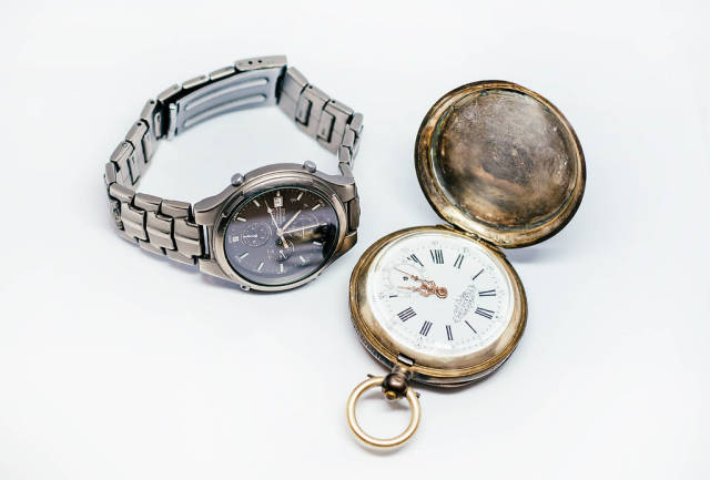 Alte Taschenuhr und moderne Armbanduhr aus Titanium vor weißem Hintergrund