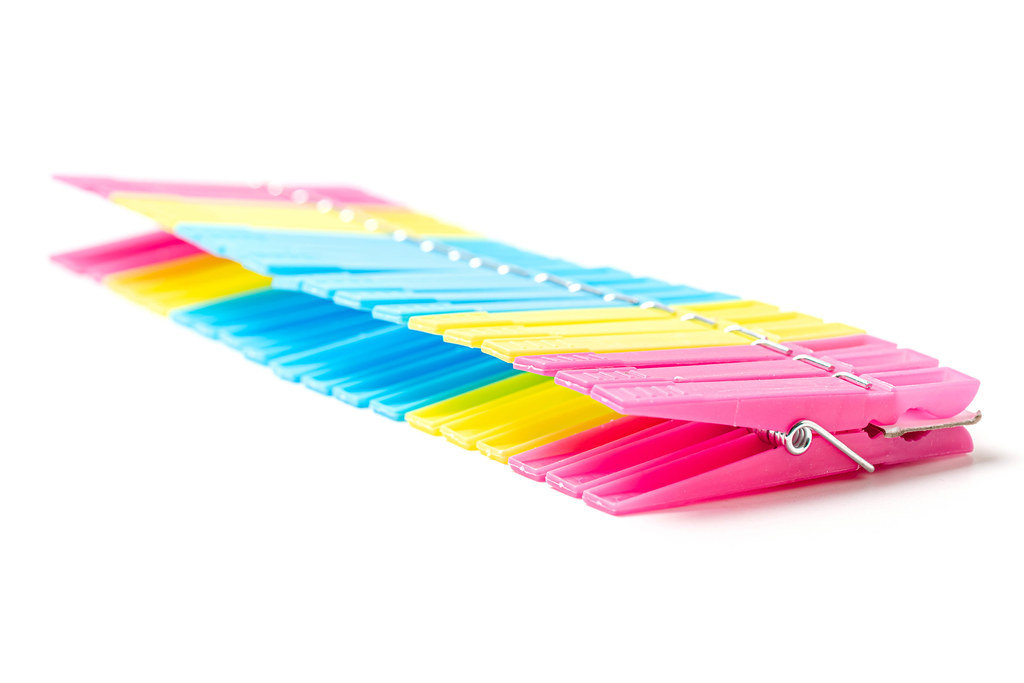 Multicolored plastic clothespins on white background