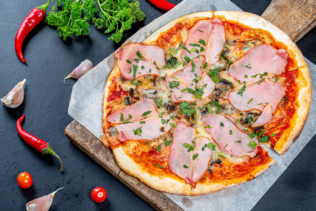 Delicious fresh pizza with ham and mushrooms