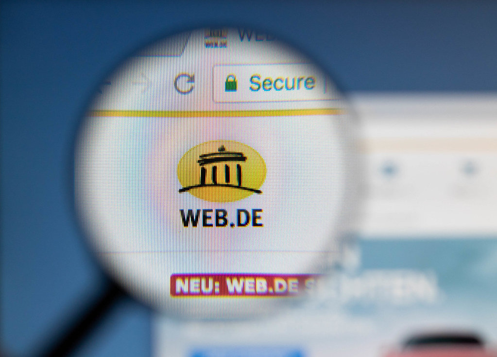 Web.de Logo am PC-Monitor, durch eine Lupe fotografiert