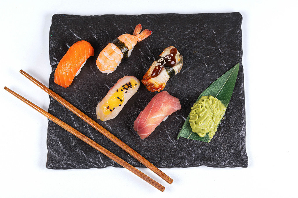 Fresh nigiri on a black stone tray with hot wasabi sauce, top view