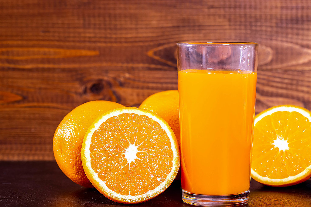 A glass of fresh orange juice with fruit oranges