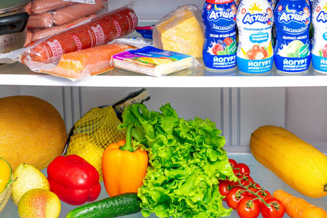Open fridge with fresh vegetables, fruits and other products inside