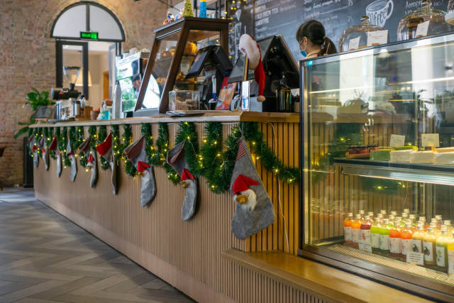 Christmas Decorations with String Lights, Stockings and Garlands on a Cafe Counter with Display Fridge and Cashier