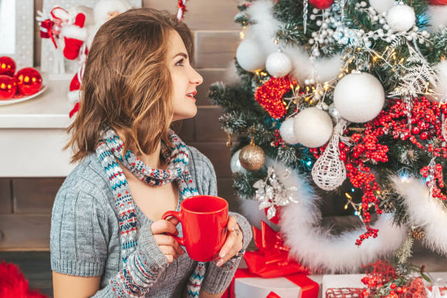 Girl with a red cup in her hands near the christmas tree