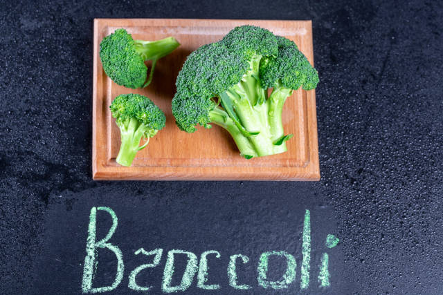 Fresh broccoli with drops of water on the kitchen Board with the inscription