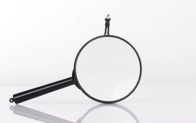 Businessman standing on magnifying glass