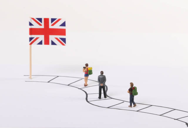 Miniature people walking on a path to the flag of United Kingdom
