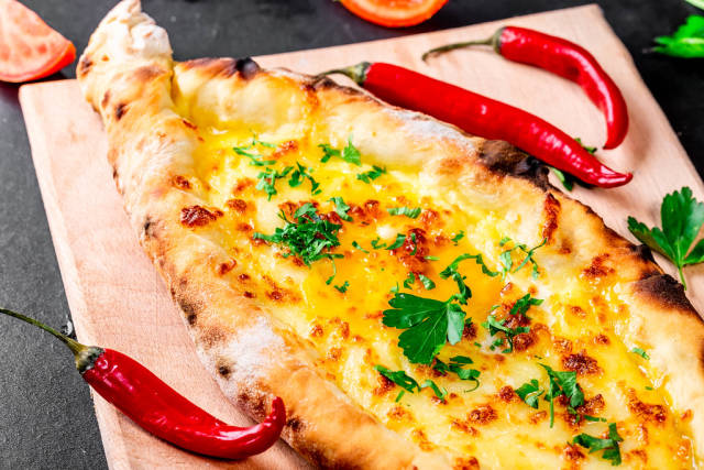 Hot open khachapuri with chicken egg and greens with chilli pepper