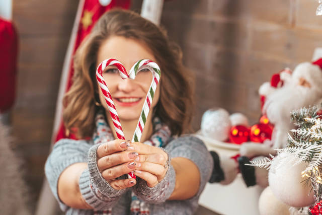 Close-up, a heart made of candy cane in the hands of a girl