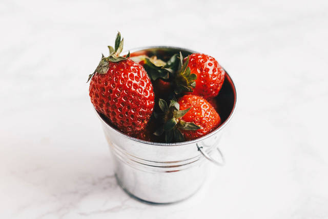 Nahaufnahme von frisch gepflückten Erdbeeren in kleinem Blecheimer