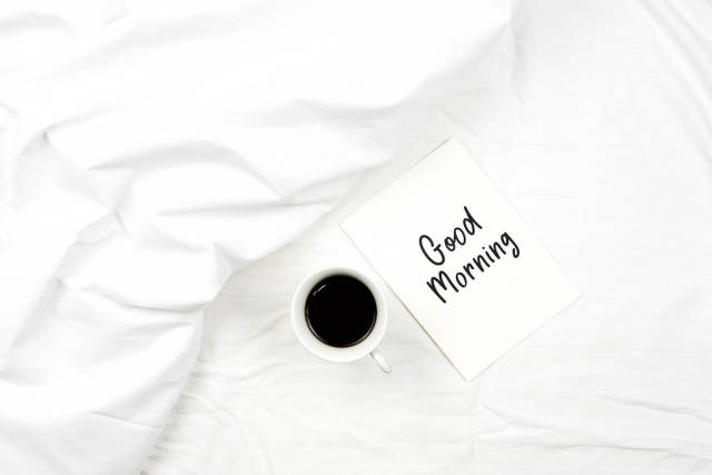 Having coffee in bed with a Good morning greeting card