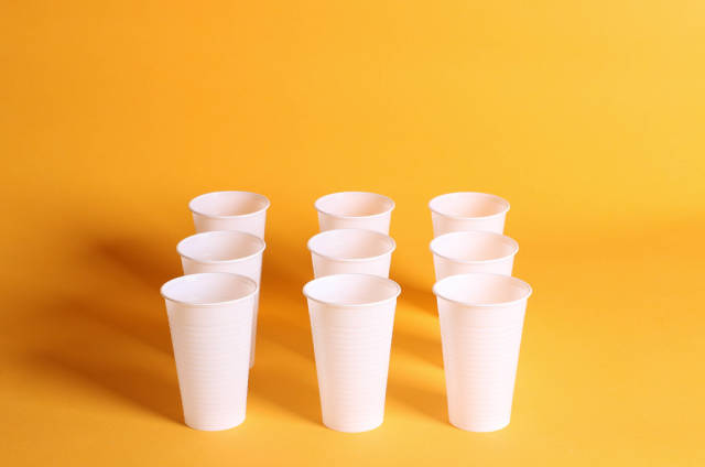 White plastic cups on a orange background