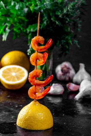 Shrimp on a wooden skewer with lemon and herbs