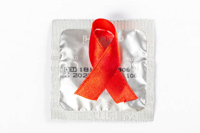 Red ribbon on a packed condom, AIDS prevention