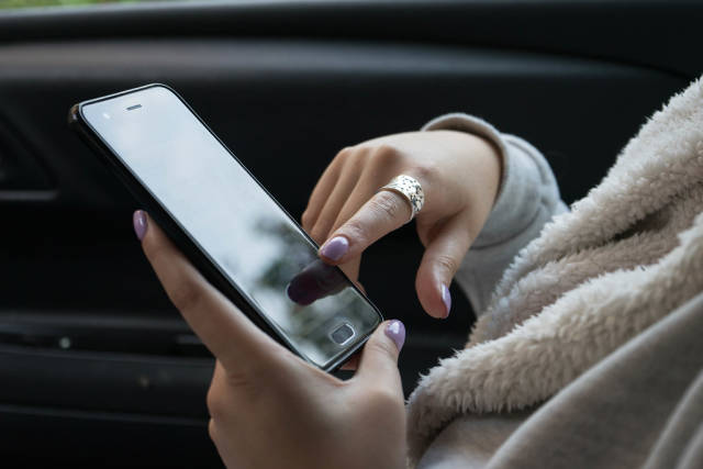 Midsection of a Woman using the Smartphone in the Car
