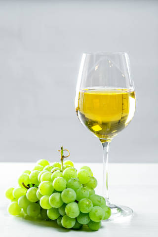 Grapes and white wine glass on a wooden table, front view