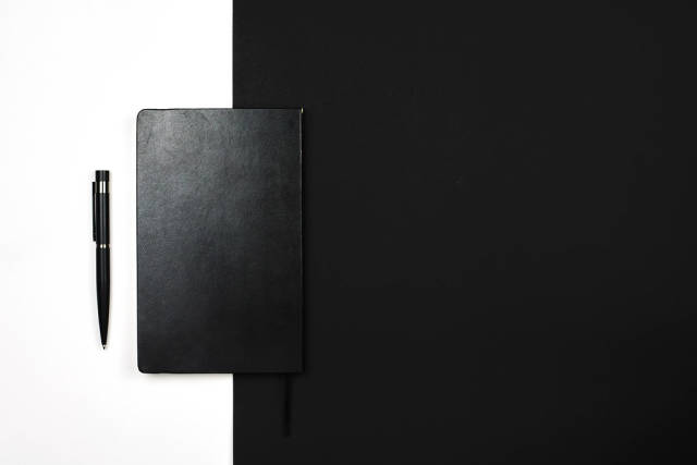 A black leather notepad on black and white background