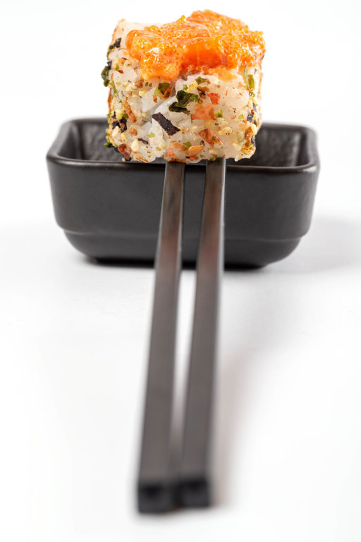 Spicy roll with tobiko caviar, sauce and chopsticks