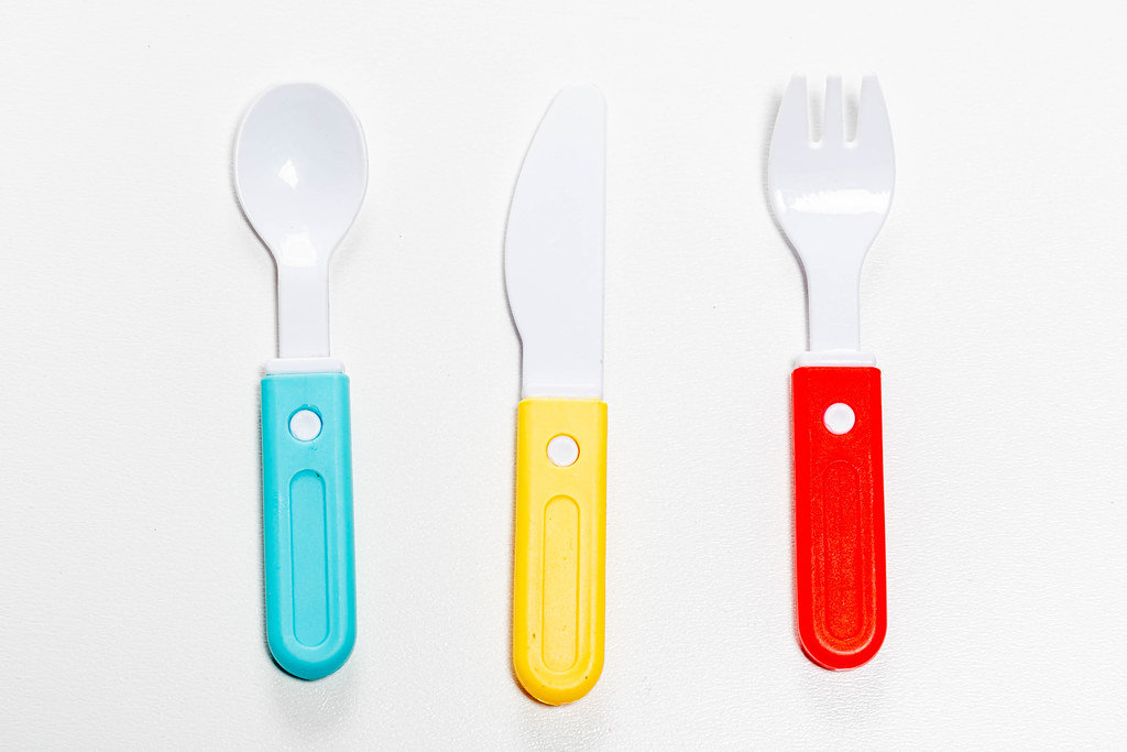Plastic knife, fork and spoon on white background. Childrens toy