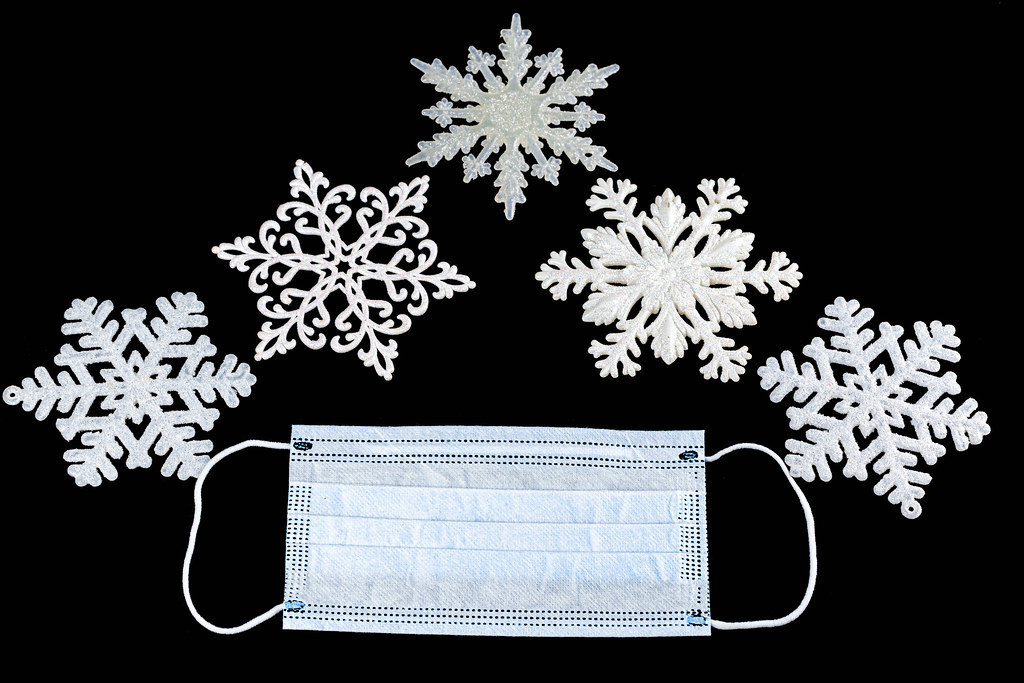 Christmas white snowflakes and medical mask on black background