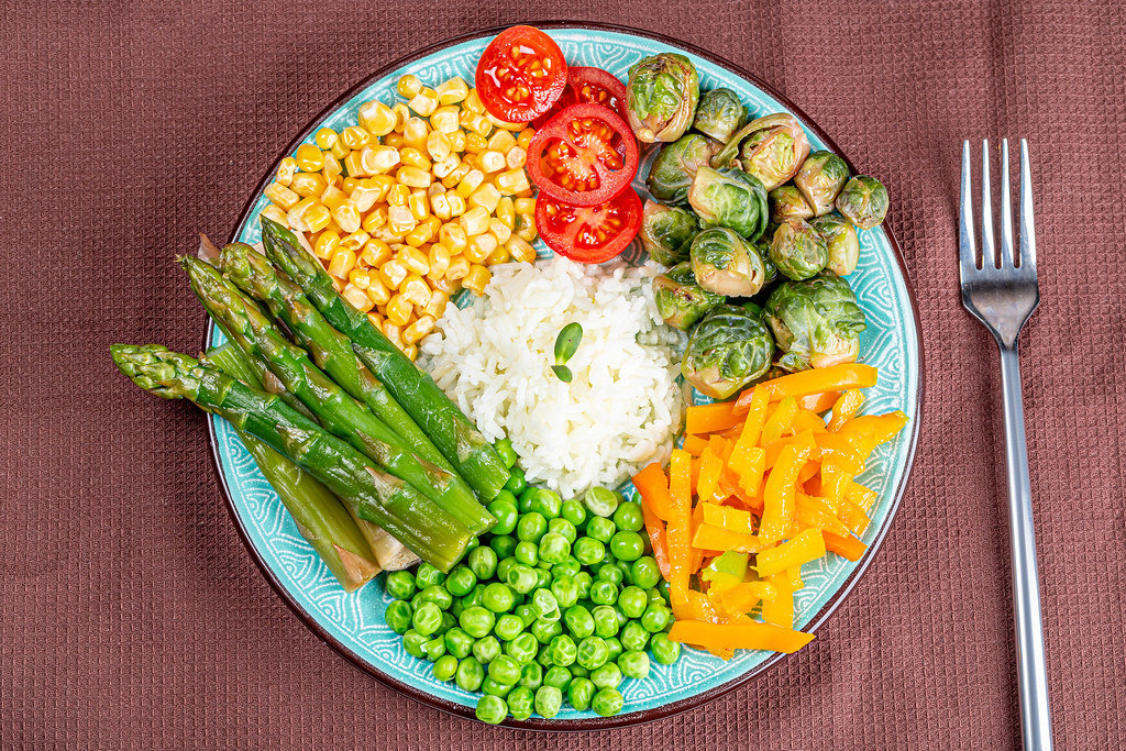 Rice with vegetables on a brown kitchen towel with a fork, top view