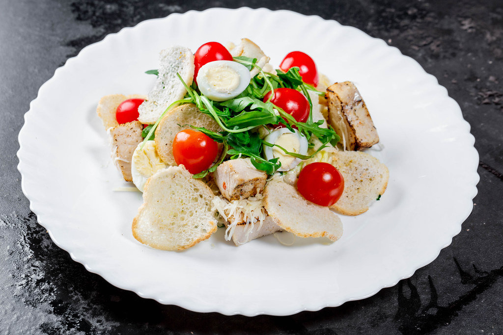 Salad with chicken fillet, vegetables, herbs, croutons and Parmesan
