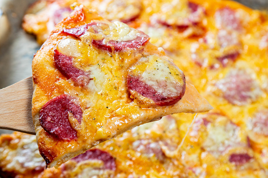 Close-up of a piece of hot pizza with cheese and sausage