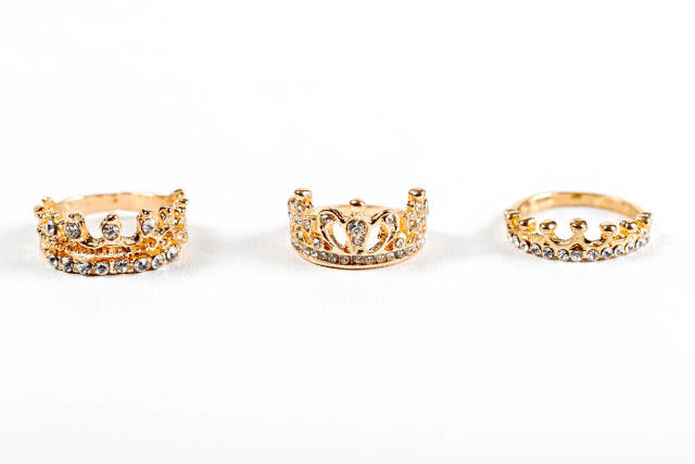 Three crown-shaped rings with stones on a white background
