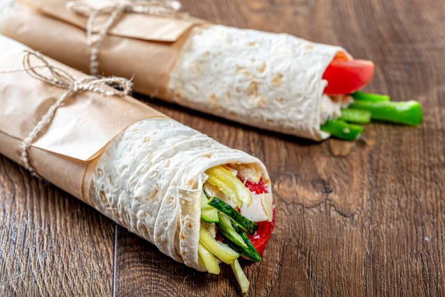 Two ready-made Shawarma on a brown wooden background