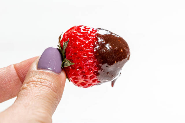Close-up of fresh strawberries in milk chocolate in a womans hand