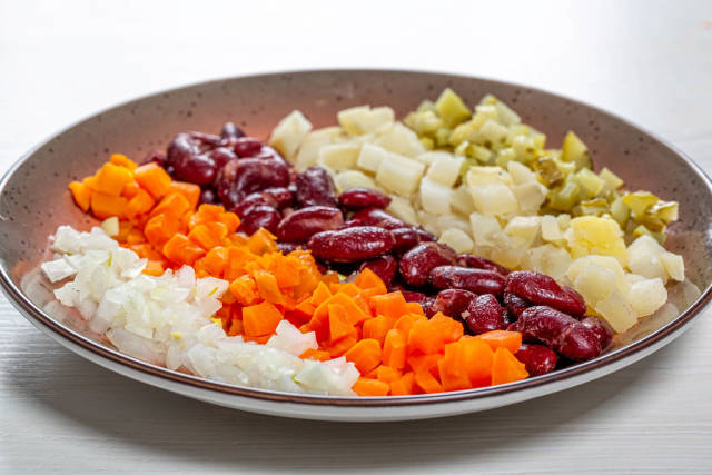 Plate with sliced boiled vegetables and pickles with onions