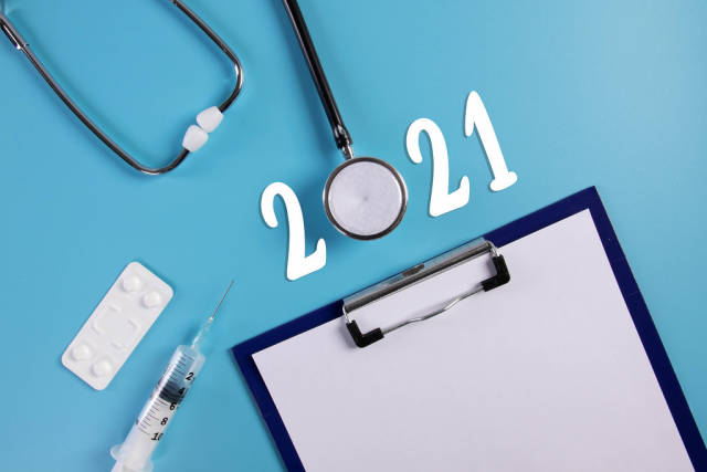 Clipboard, stethoscope, syringe and pills with 2021 text on blue background