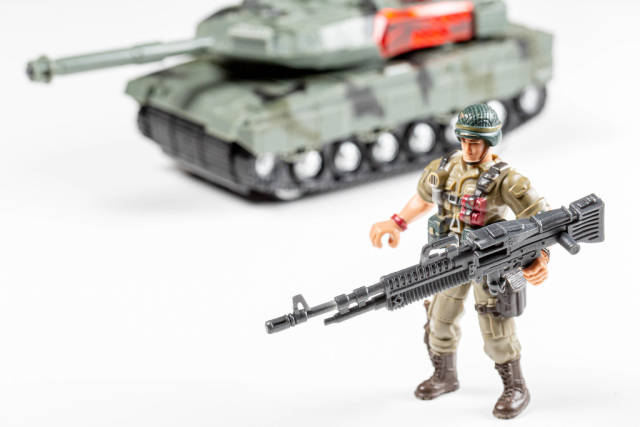 Toys soldiers with weapons in their hands and a tank behind him