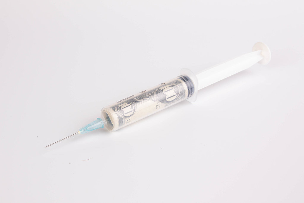 Money in syringe on white background