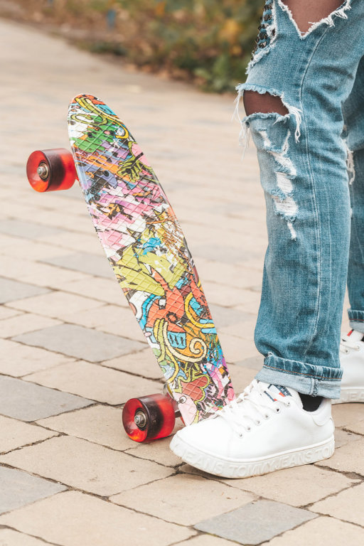 Skateboard and girl legs in city park