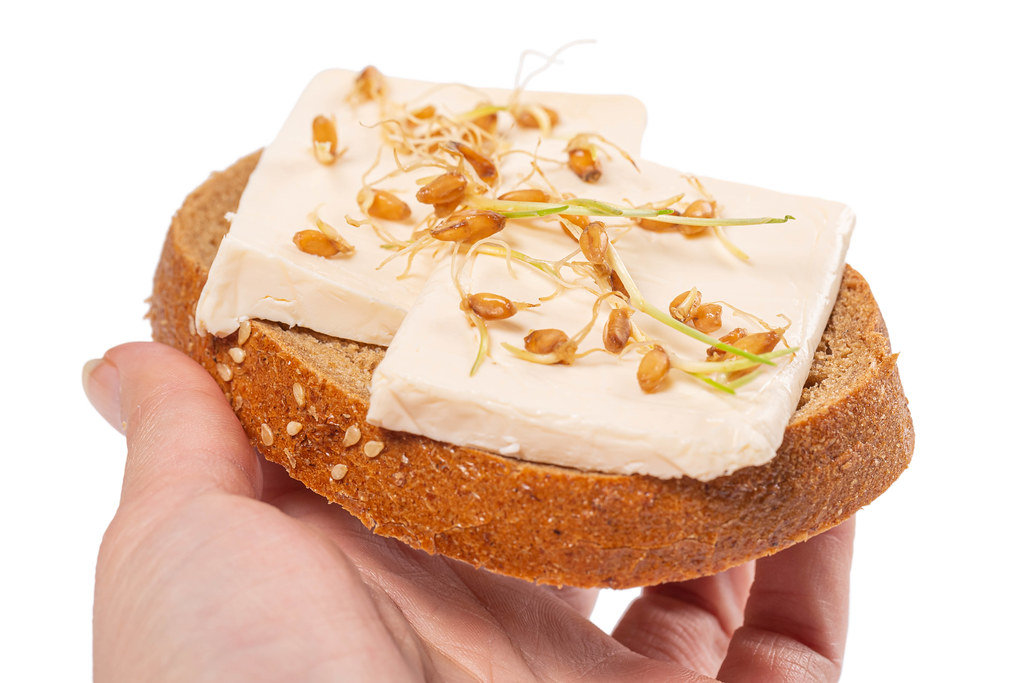 Sandwich with cheese and sprouted wheat in a womans hand