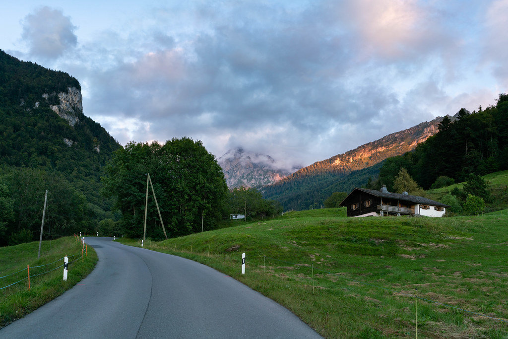 Beautiful Swiss country road going up the mountains with sunset mountain peak at the end