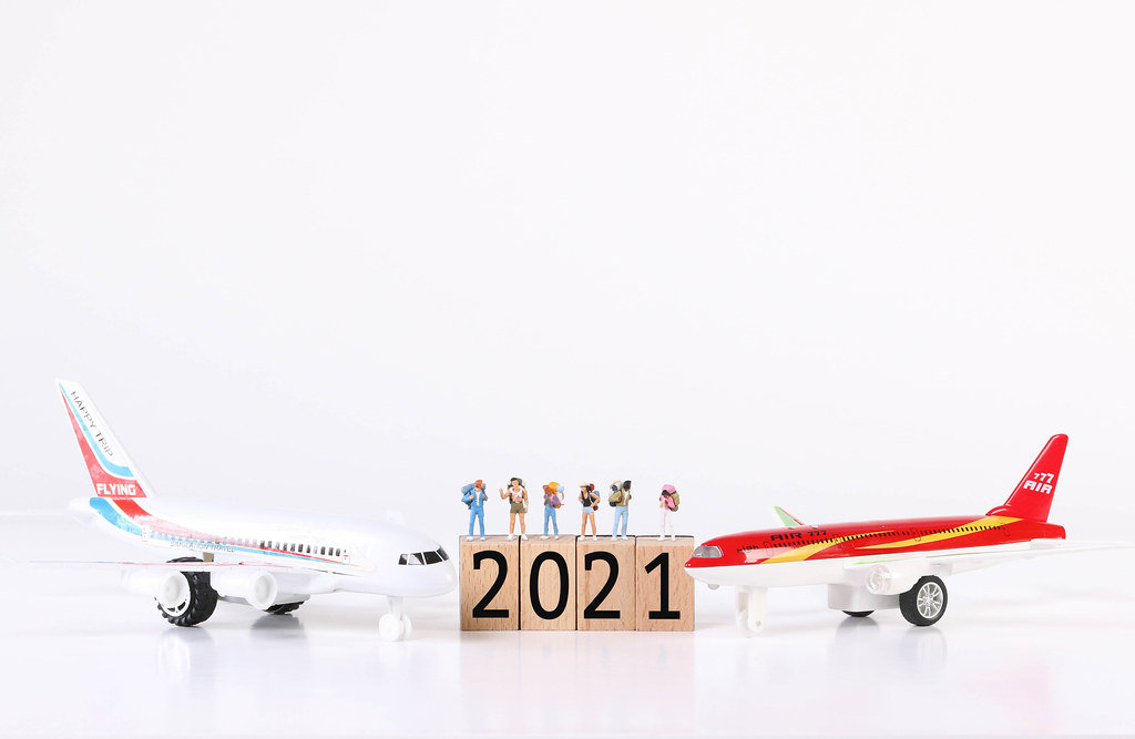 Miniature travelers with toy airplanes and 2021 text